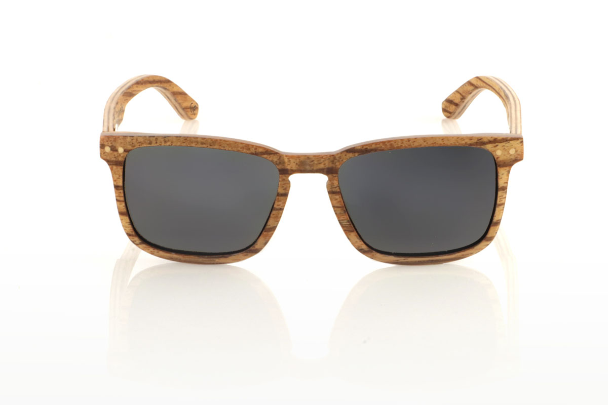 Gafas de Madera Natural de Zebrano ROMUALD. Las gafas de sol de madera ROMUALD destacan por su diseño, íntegramente elaborado con madera de zebrano laminada de color claro y una veta marcada, que les confiere una presencia distintiva y natural. Su forma más cuadrada se adapta perfectamente a rostros más pequeños, ofreciendo una estética equilibrada y atractiva. Las incrustaciones redondas de madera de arce del frontal aportan un detalle delicado. Con unas medidas de 135x41 y un calibre de 50, estas gafas son ideales para quienes buscan un accesorio con personalidad y estilo. Venta al Por Mayor y Detalle | Root Sunglasses® 